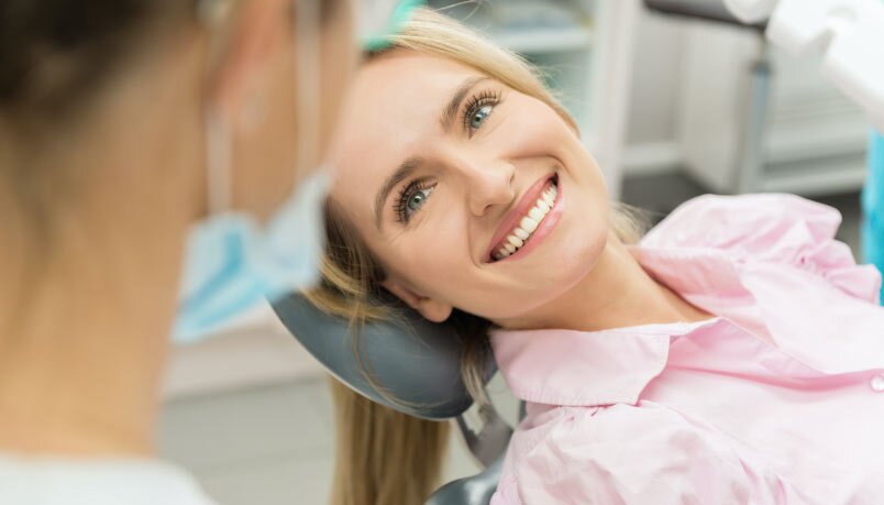 A smiling woman in a dental chair, wearing a pink blouse, at a dental office possibly for sedation dentistry in Sandpoint, Idaho.